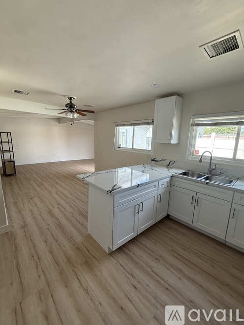 A kitchen with white cabinets and a wooden floor.