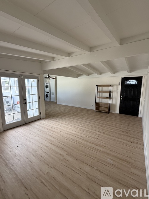 A spacious room with wooden flooring and white walls.