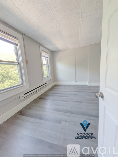 A room with a white door and a window with a view of trees.