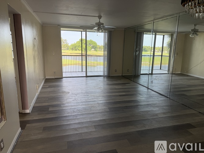 A spacious room with wooden flooring and sliding glass doors leading to a balcony.