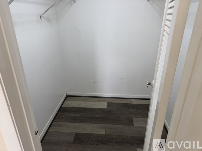 A small, empty room with wooden flooring and white walls.
