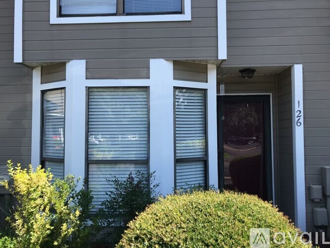 A grey house with a white door and window.