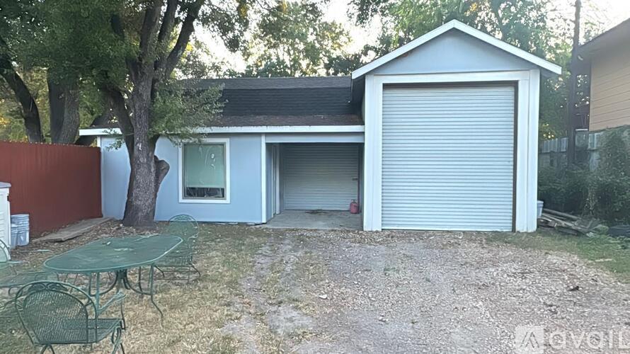 A blue house with a white garage door and a green table in front.