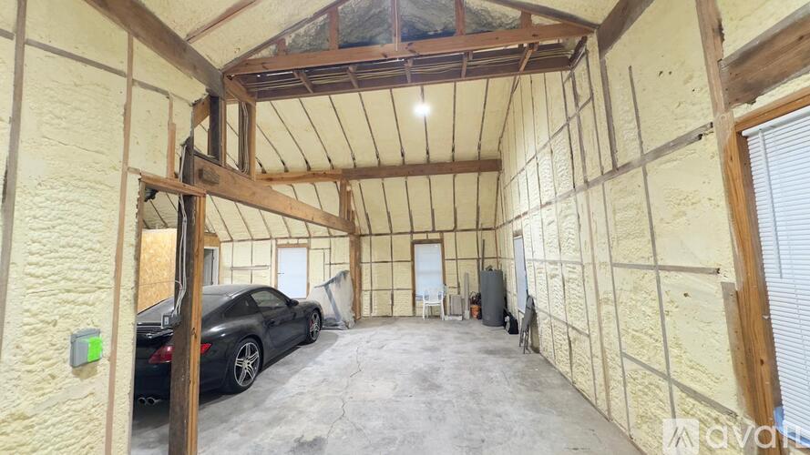 A car is parked in a garage with wooden walls and a wooden roof.