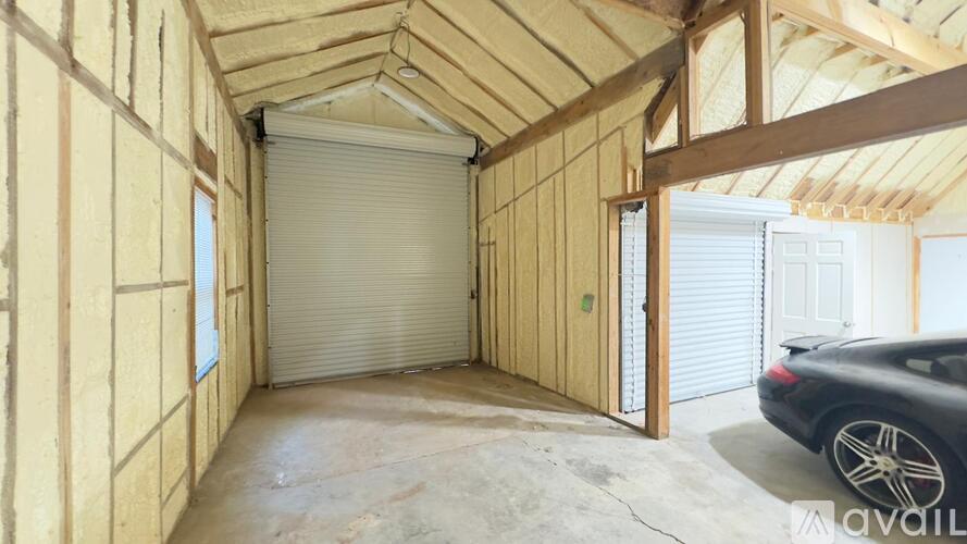 A car is parked in a garage with a roller shutter door.