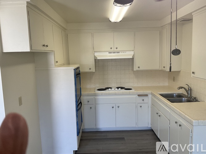 A kitchen with white cabinets and a black refrigerator.