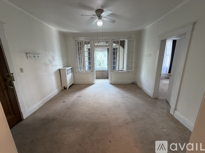 A spacious room with a ceiling fan and large windows.