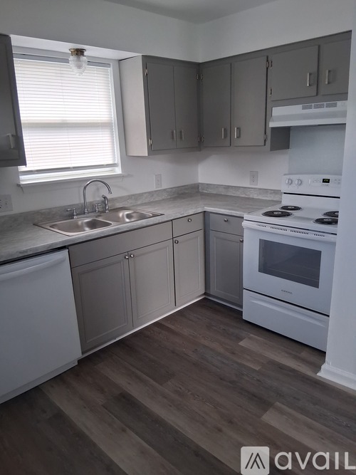 A kitchen with white appliances and wooden floors.
