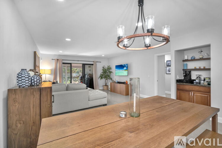 A modern living room with a wooden dining table and a chandelier.