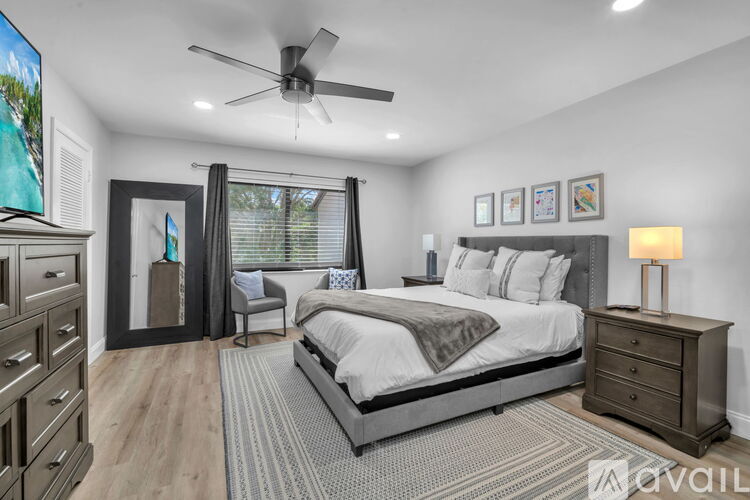 A bedroom with a large bed, a ceiling fan, and a dresser.