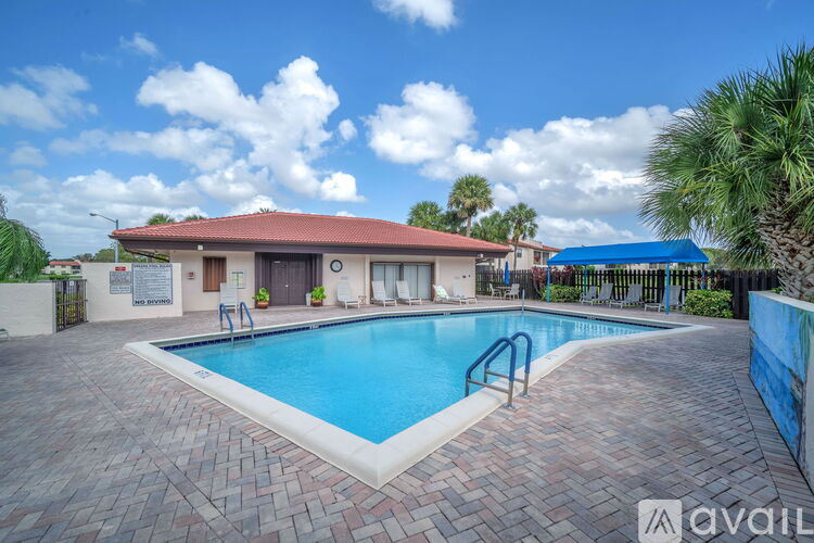 A pool surrounded by a brick patio with a building in the background.