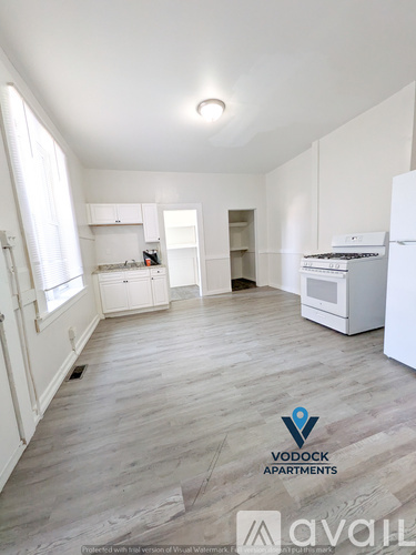 A spacious, empty apartment with wood flooring and white walls.