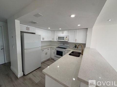 A kitchen with white cabinets and appliances, a sink, and a countertop.