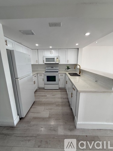 A modern kitchen with white appliances and cabinets.