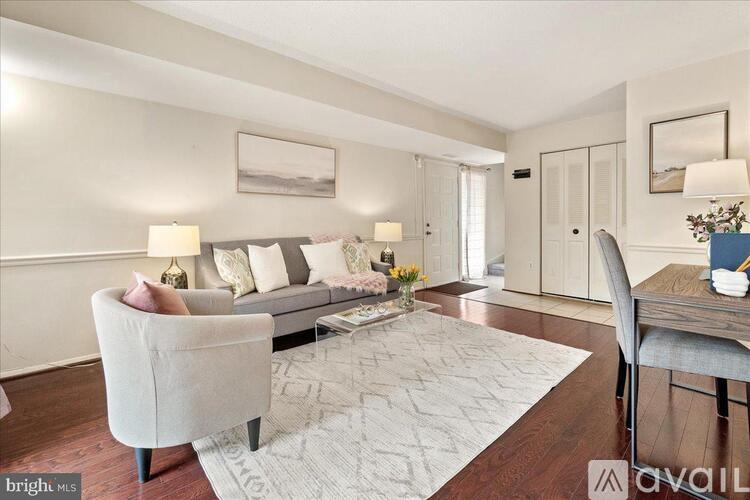 A well-lit living room with a grey sofa, a grey armchair, and a patterned rug.
