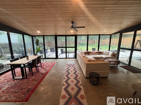 A living room with a rug, a couch, a table and chairs, and a ceiling fan.
