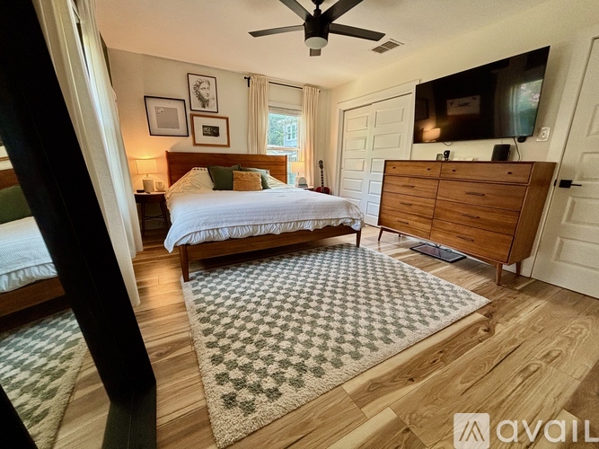 A bedroom with a bed, dresser, and ceiling fan.
