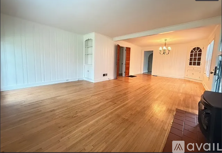 A spacious room with wooden flooring and white walls.