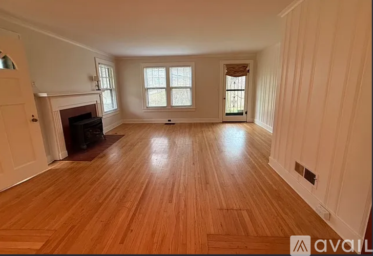 A spacious room with wooden flooring and a fireplace.
