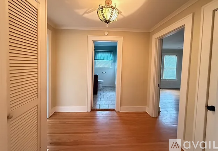 A hallway with a wooden floor and a light hanging from the ceiling.