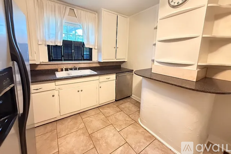 A kitchen with white cabinets and a tiled floor.
