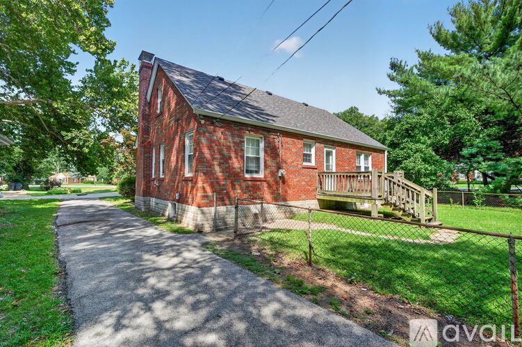 A red brick house with a porch and a fence.
