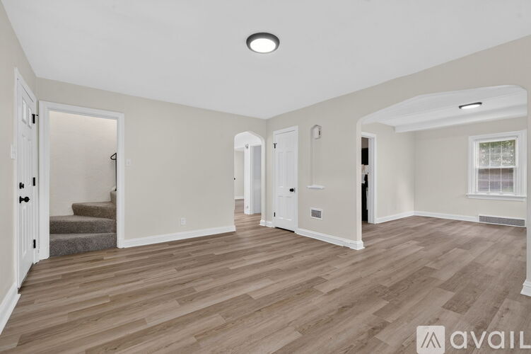 A spacious room with wooden flooring and white walls.