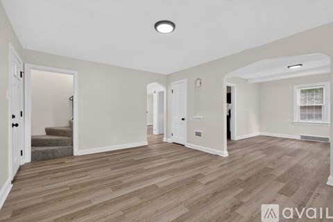 A spacious room with wooden flooring and white walls.