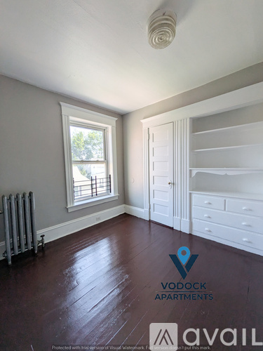A room with wooden floors and a window with a view of trees.