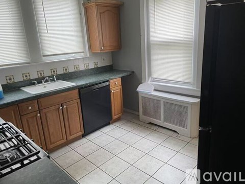 A kitchen with a black fridge, white sink and a black stove top.