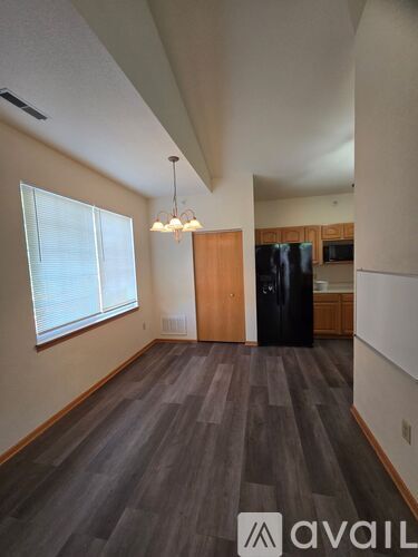 A room with a wooden floor and a black refrigerator.