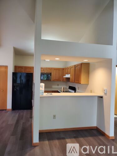 A kitchen with a black fridge and wooden cabinets.