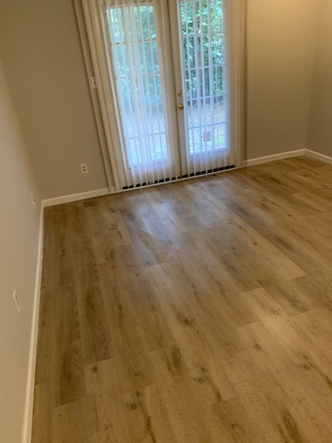 A room with a wooden floor and a sliding glass door.