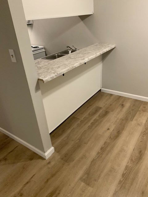 A kitchen with a marble countertop and wooden flooring.