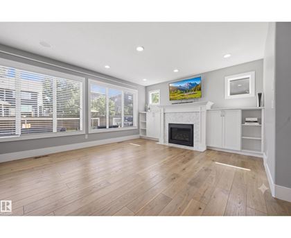 A spacious living room with a fireplace and a television mounted on the wall.