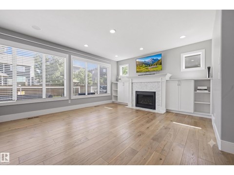 A spacious living room with a fireplace and a television mounted on the wall.