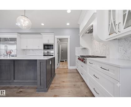 A modern kitchen with white cabinets and a dark island.