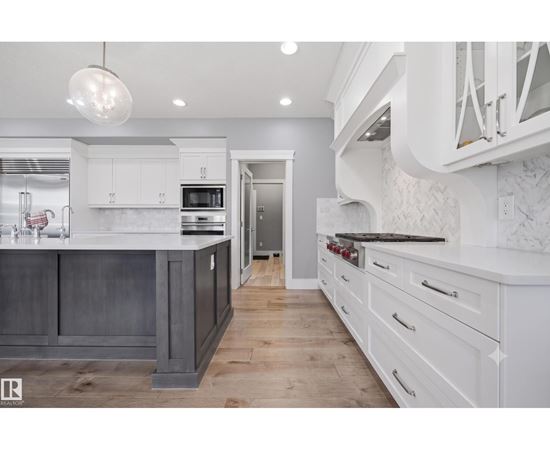 A modern kitchen with white cabinets and a dark island.