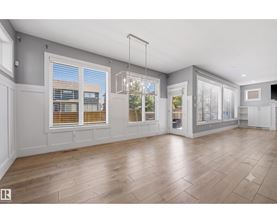 A spacious room with wooden flooring and large windows.