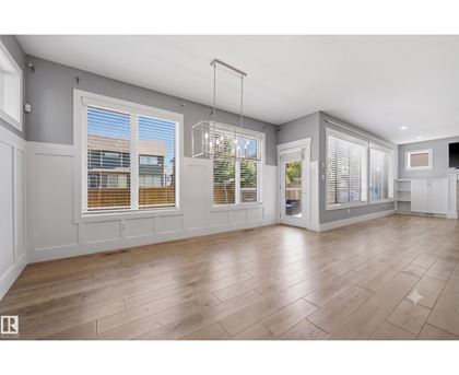 A spacious room with wooden flooring and large windows.