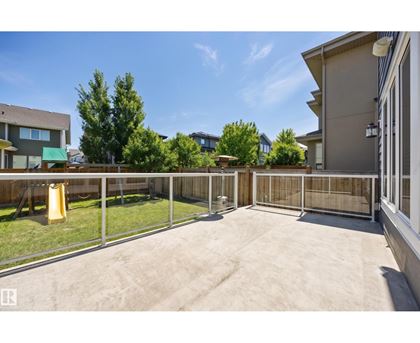 A backyard with a fence and a yellow trash can.
