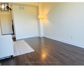 A room with wooden flooring and a white rug.