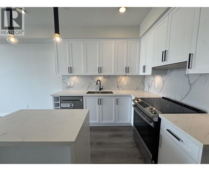 A kitchen with white cabinets and marble countertops.