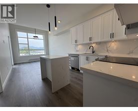 A kitchen with white cabinets and a marble countertop.