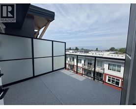 A balcony with a glass railing and a view of other buildings.