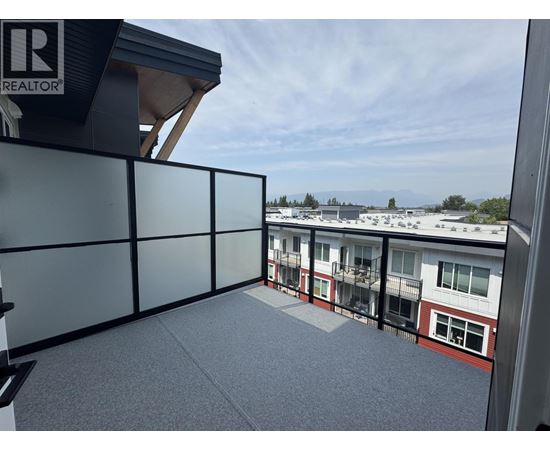 A balcony with a glass railing and a view of other buildings.