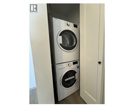 A washing machine is in a small space between a door and a wall.