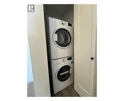 A washing machine is in a small space between a door and a wall.