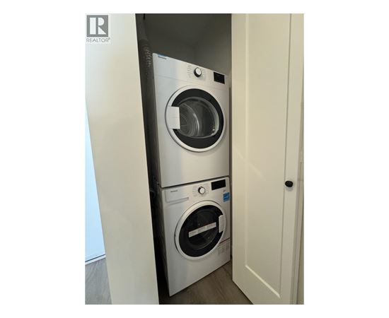 A washing machine is in a small space between a door and a wall.