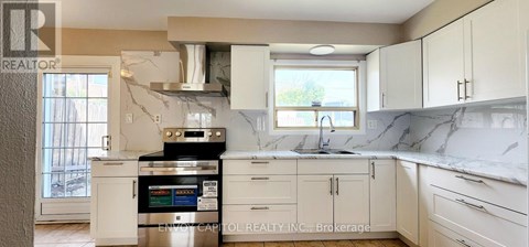 A kitchen with white cabinets and a marble countertop.